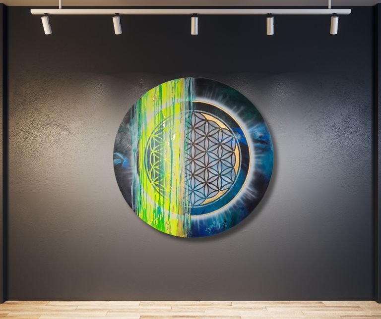Rundes Kunstwerk mit einem Muster aus Blume des Lebens, geteilt in eine leuchtend grüne und eine blaue Hälfte, hängt an einer schwarzen Wand unter fünf Deckenstrahlern.
